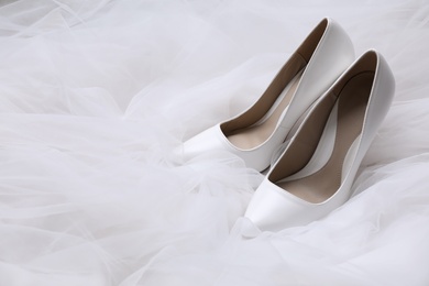 Photo of Pair of wedding high heel shoes on white veil