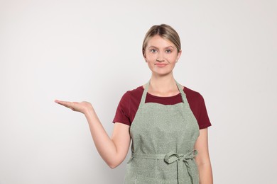Photo of Beautiful young woman in clean apron on light grey background