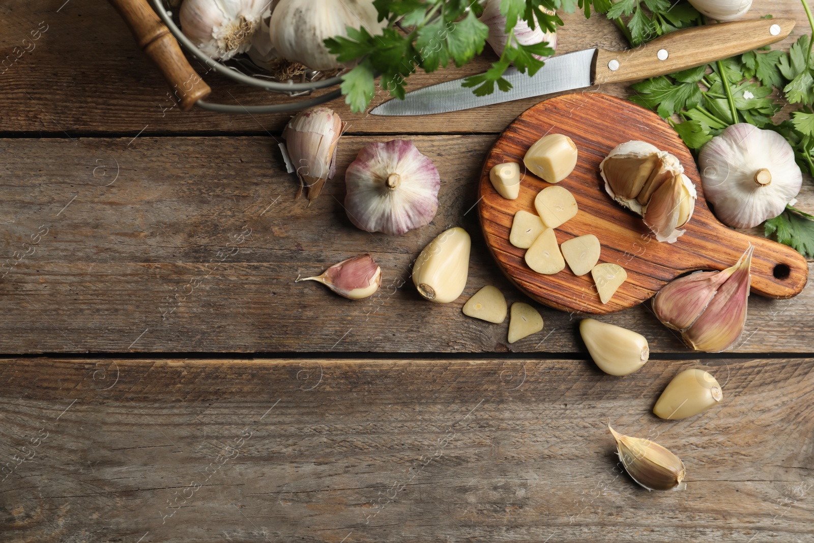 Photo of Flat lay composition with fresh sliced and whole garlic on wooden table, space for text. Organic product