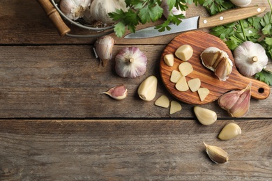 Photo of Flat lay composition with fresh sliced and whole garlic on wooden table, space for text. Organic product