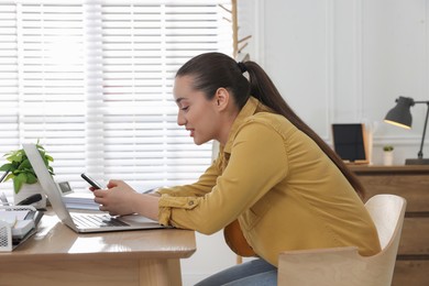 Photo of Young woman with poor posture using smartphone at table indoors