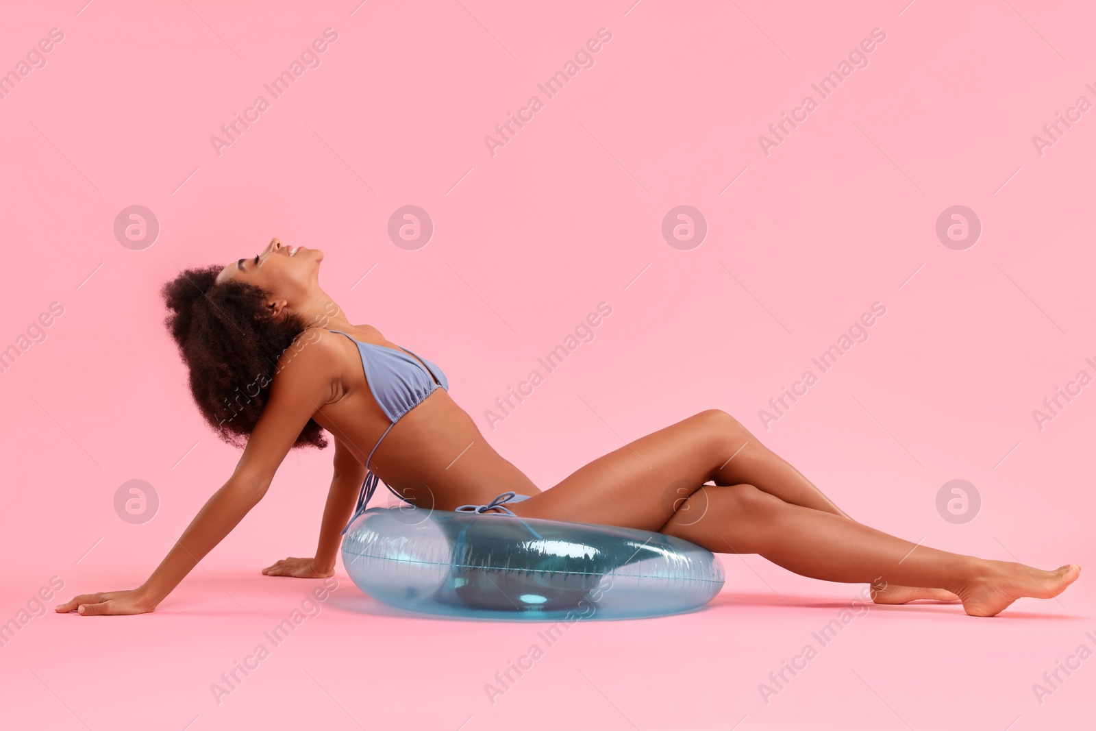 Photo of Beautiful woman in stylish bikini with inflatable ring on pink background