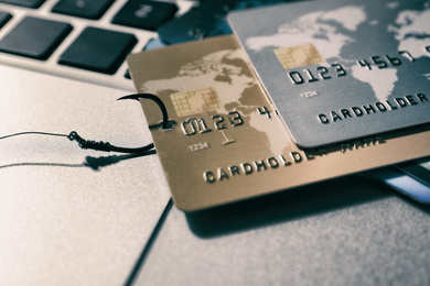 Photo of Fishing hook with credit cards on laptop, closeup. Cyber crime