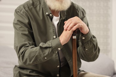 Photo of Senior man with walking cane indoors, closeup