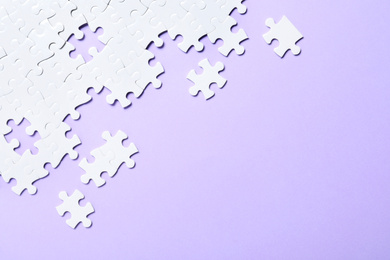 Photo of Blank white puzzle pieces on violet background, flat lay. Space for text