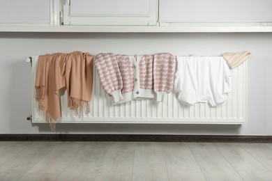Photo of Clean clothes on heating radiator near window indoors