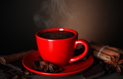 Photo of Cup of delicious hot chocolate, spices and coffee beans on wooden table
