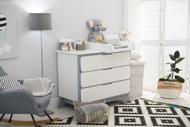 Photo of Beautiful baby room interior with modern changing table and rocking chair