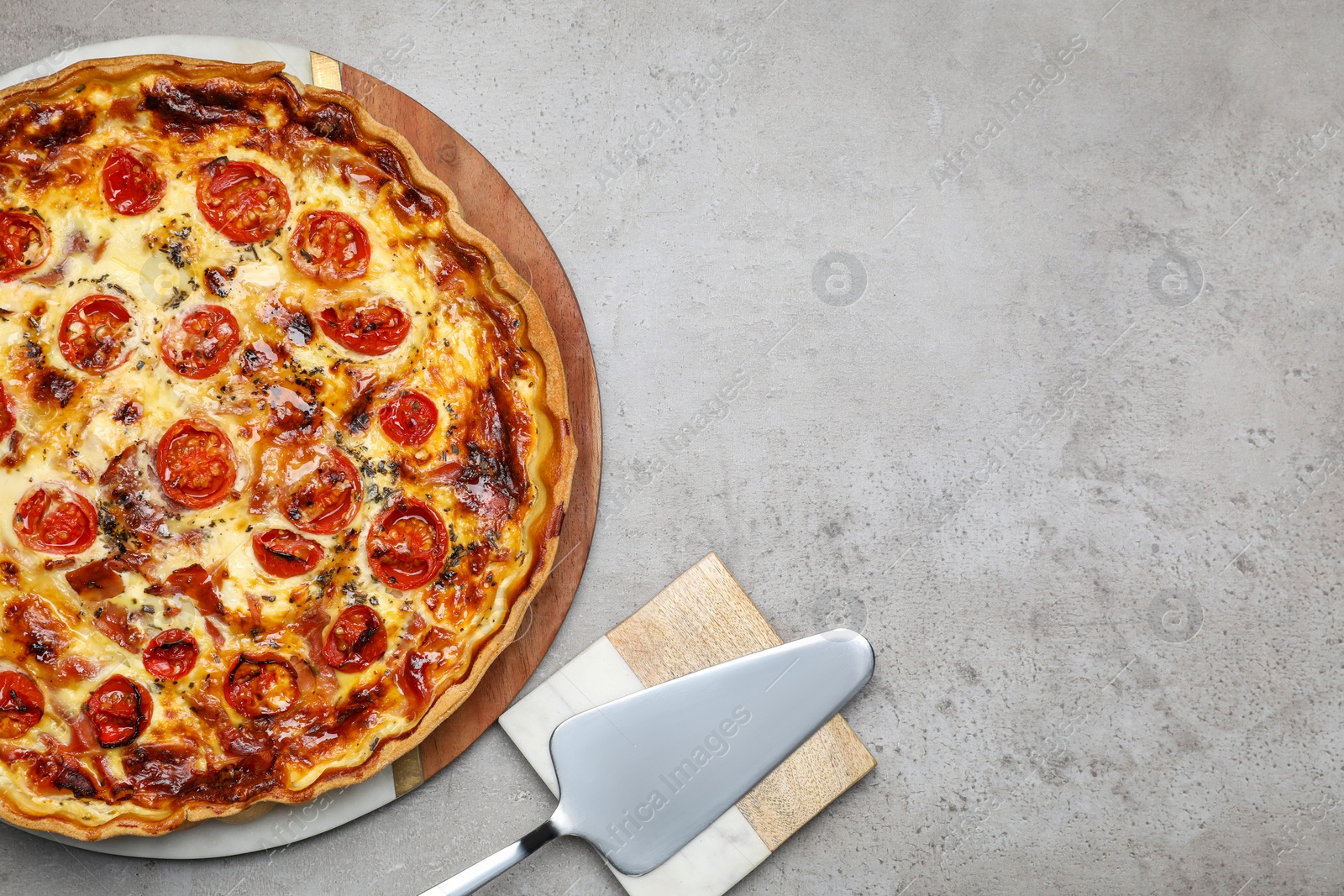 Delicious homemade prosciutto quiche and spatula on light gray table, flat lay. Space for text Photo of Delicious homemade prosciutto quiche and spatula on light gray table, flat lay. Space for text
