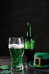 Photo of St. Patrick's day celebration. Green beer, leprechaun hat and decorative clover leaves on grey table. Space for text