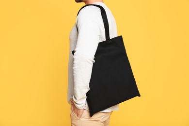 Photo of Young man with eco bag on yellow background, closeup