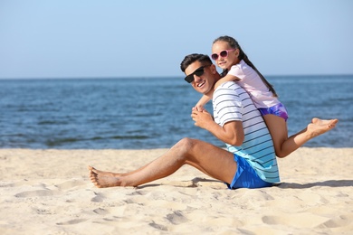 Photo of Father and daughter on sandy beach near sea. Summer holidays with family