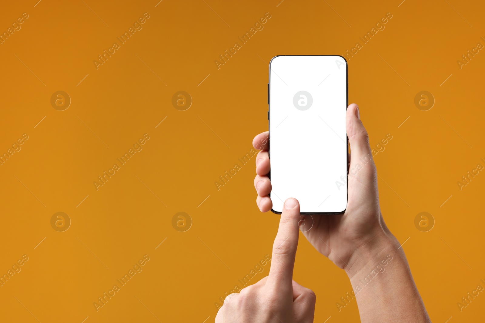 Photo of Man using smartphone with blank screen on orange background, closeup. Mockup for design