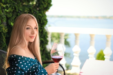 Photo of Beautiful woman with glass of wine on restaurant terrace