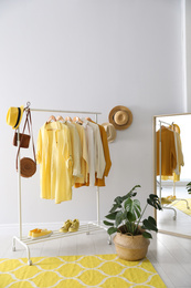 Photo of Rack with stylish women's clothes and mirror indoors. Interior design