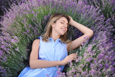 Photo of Young woman lying in lavender field on summer day