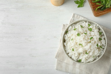 Photo of Bowl of boiled rice served on wooden table, top view with space for text