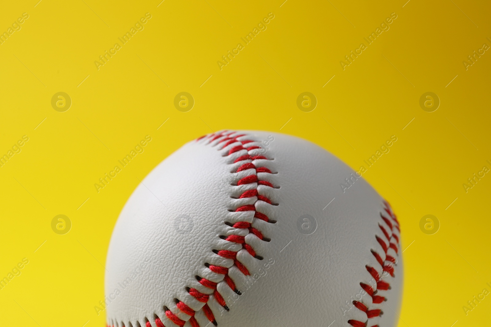 Photo of One baseball ball on yellow background, closeup