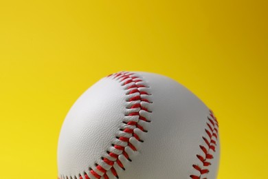 One baseball ball on yellow background, closeup