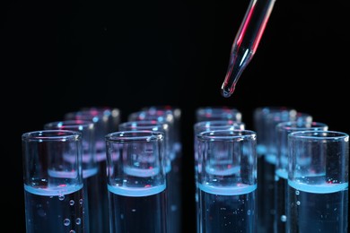 Dripping reagent into test tube on black background, closeup. Laboratory analysis