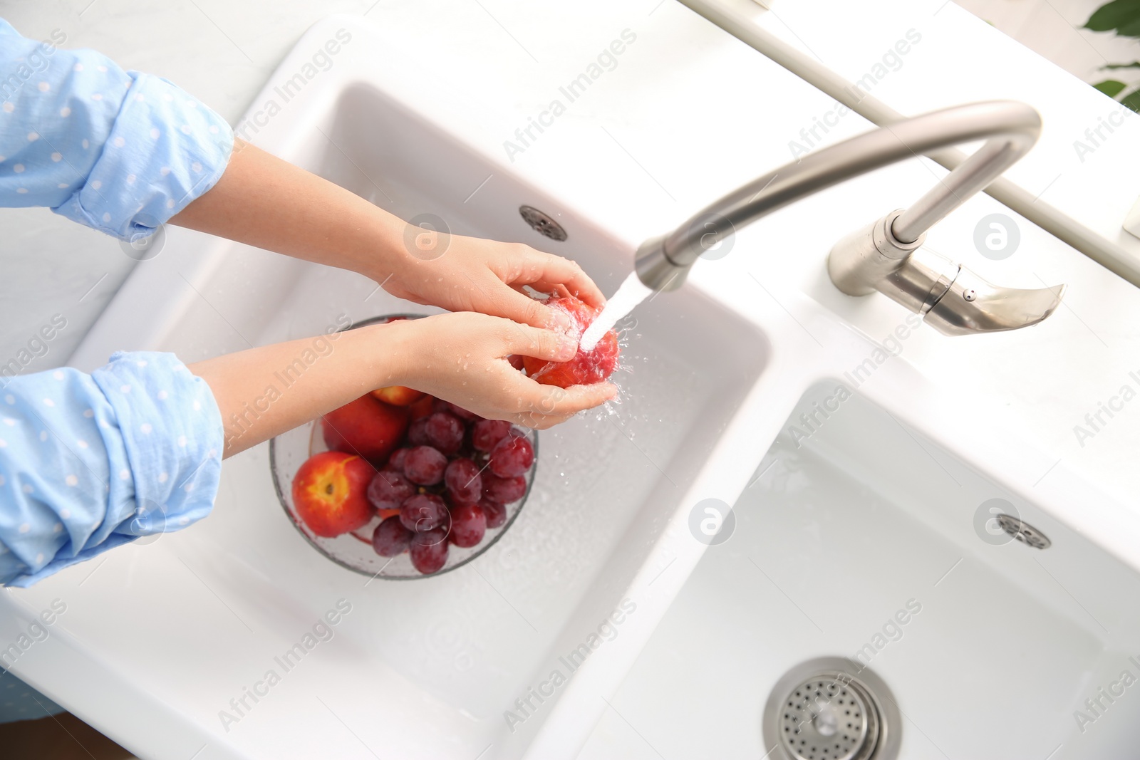 Photo of Woman washing fresh nectarine in kitchen sink, top view