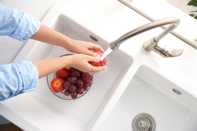 Photo of Woman washing fresh nectarine in kitchen sink, top view