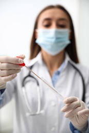 Photo of Doctor holding buccal cotton swab and tube for DNA test in clinic, focus on hands