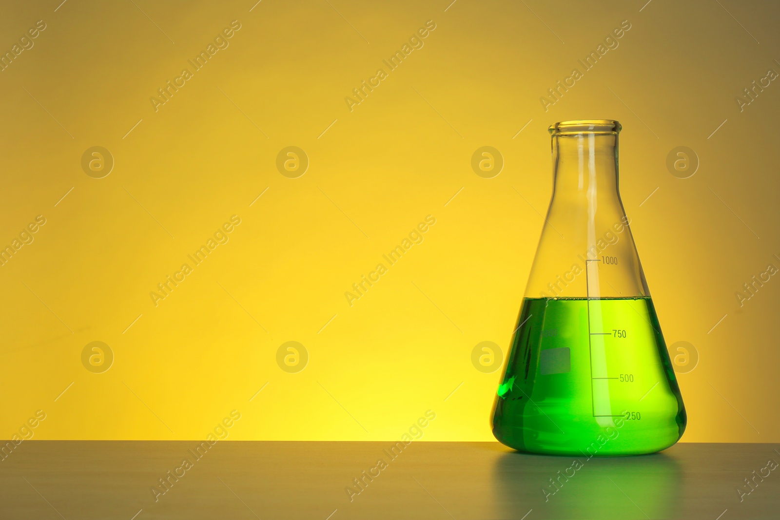 Photo of Conical flask with liquid on table against color background. Chemistry laboratory glassware