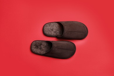 Photo of Pair of brown slippers on red background, top view