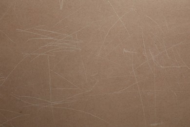 Photo of Old fiberboard with scratches as background, closeup
