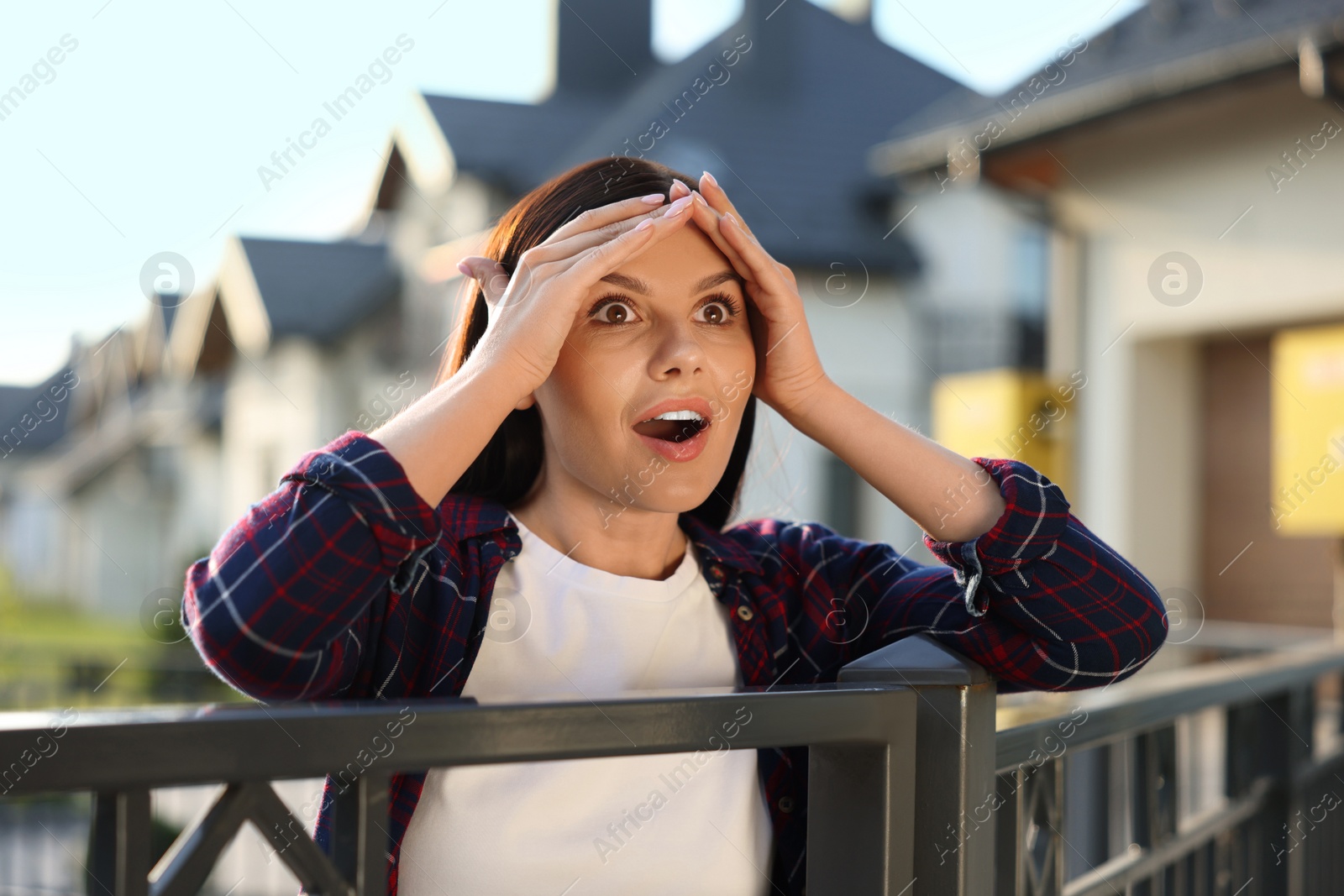 Photo of Concept of private life. Curious young woman spying on neighbours over fence outdoors