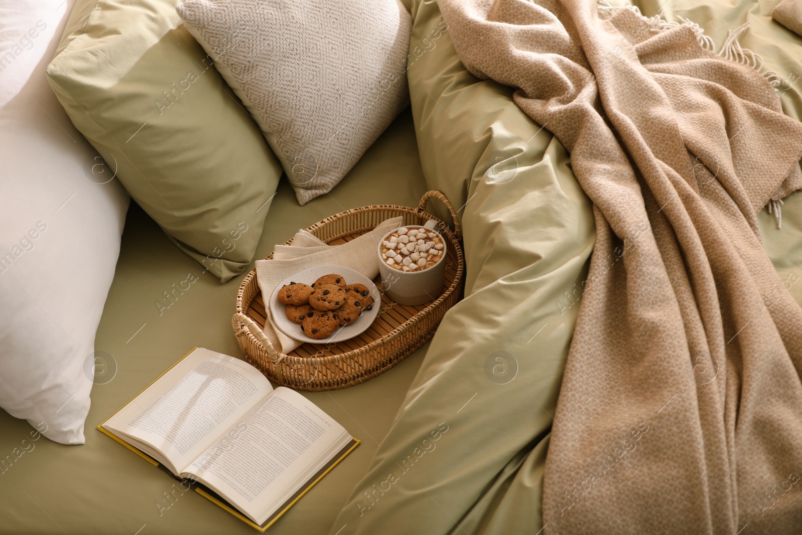 Photo of Cup of drink, cookies and book on bed with new pistachio linens