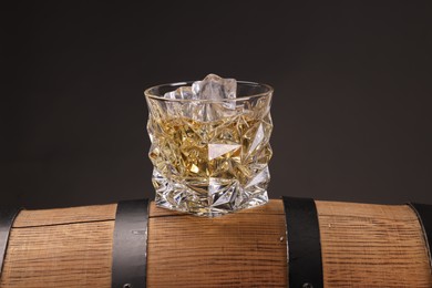 Whiskey in glass on wooden barrel against dark background