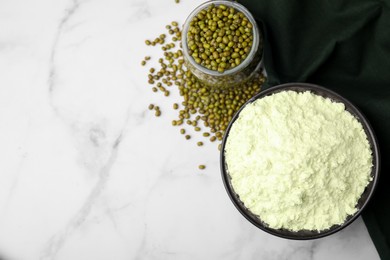 Photo of Mung bean flour in bowl and seeds on white marble table, flat lay. Space for text