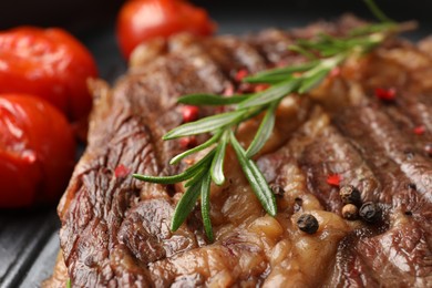 Photo of Delicious grilled beef steak, tomatoes and rosemary in frying pan, closeup