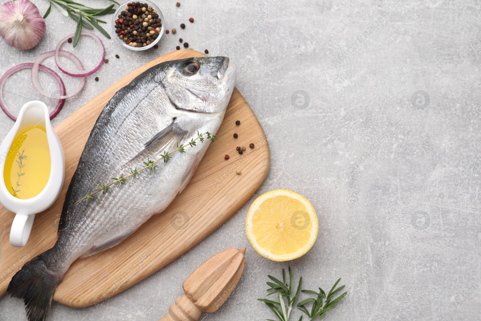 Photo of Flat lay composition with fresh raw dorado fish and ingredients on light grey table, space for text