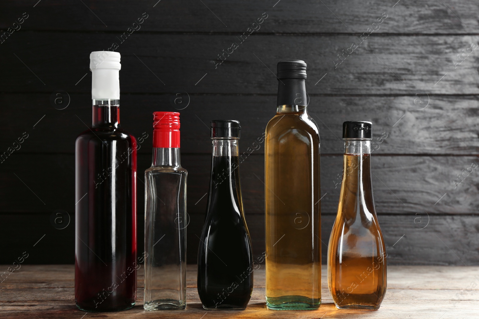 Photo of Bottles with different kinds of vinegar on wooden table