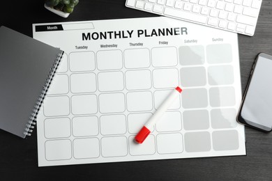 Photo of Timetable. Flat lay composition with monthly planner on black wooden table