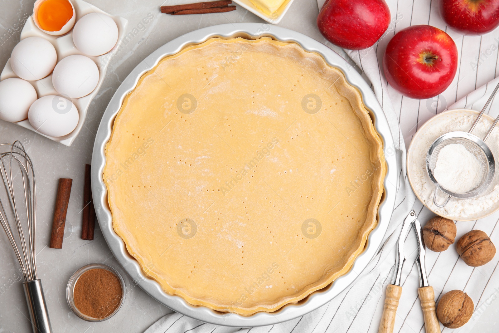 Photo of Raw dough and ingredients for traditional English apple pie on light grey marble table, flat lay