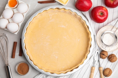 Raw dough and ingredients for traditional English apple pie on light grey marble table, flat lay