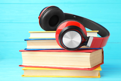Photo of Books and modern headphones on light blue wooden table