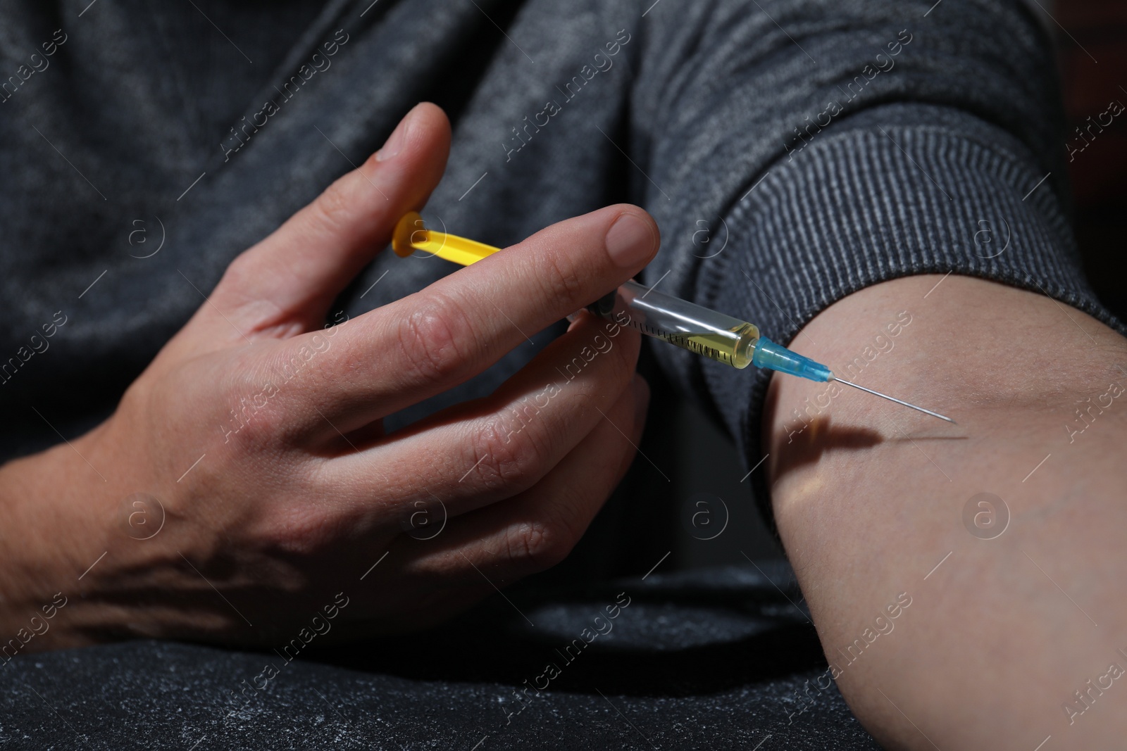 Photo of Addicted man taking drugs at black textured table, closeup