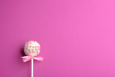 Tasty cake pop with bow on pink background, top view. Space for text