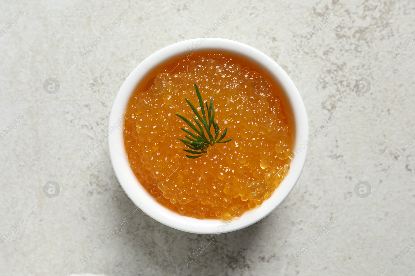 Photo of Fresh pike caviar and dill in bowl on light grey table, top view