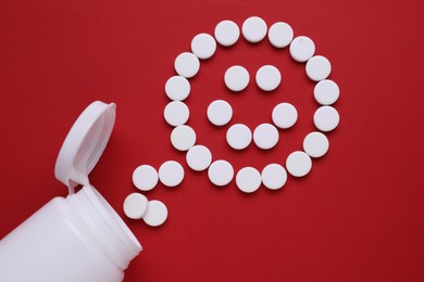 Photo of Happy emoticon made of antidepressants on red background, flat lay