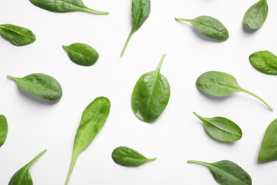 Fresh green healthy spinach leaves with water drops on white background, above view