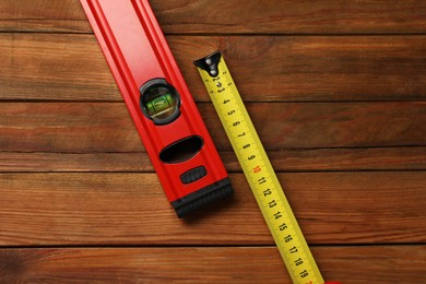 Photo of Building level and tape measure on wooden table, top view