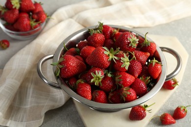 Photo of Metal colander with fresh strawberries on grey table