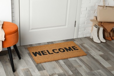 Photo of Doormat with word Welcome on wooden floor in hall