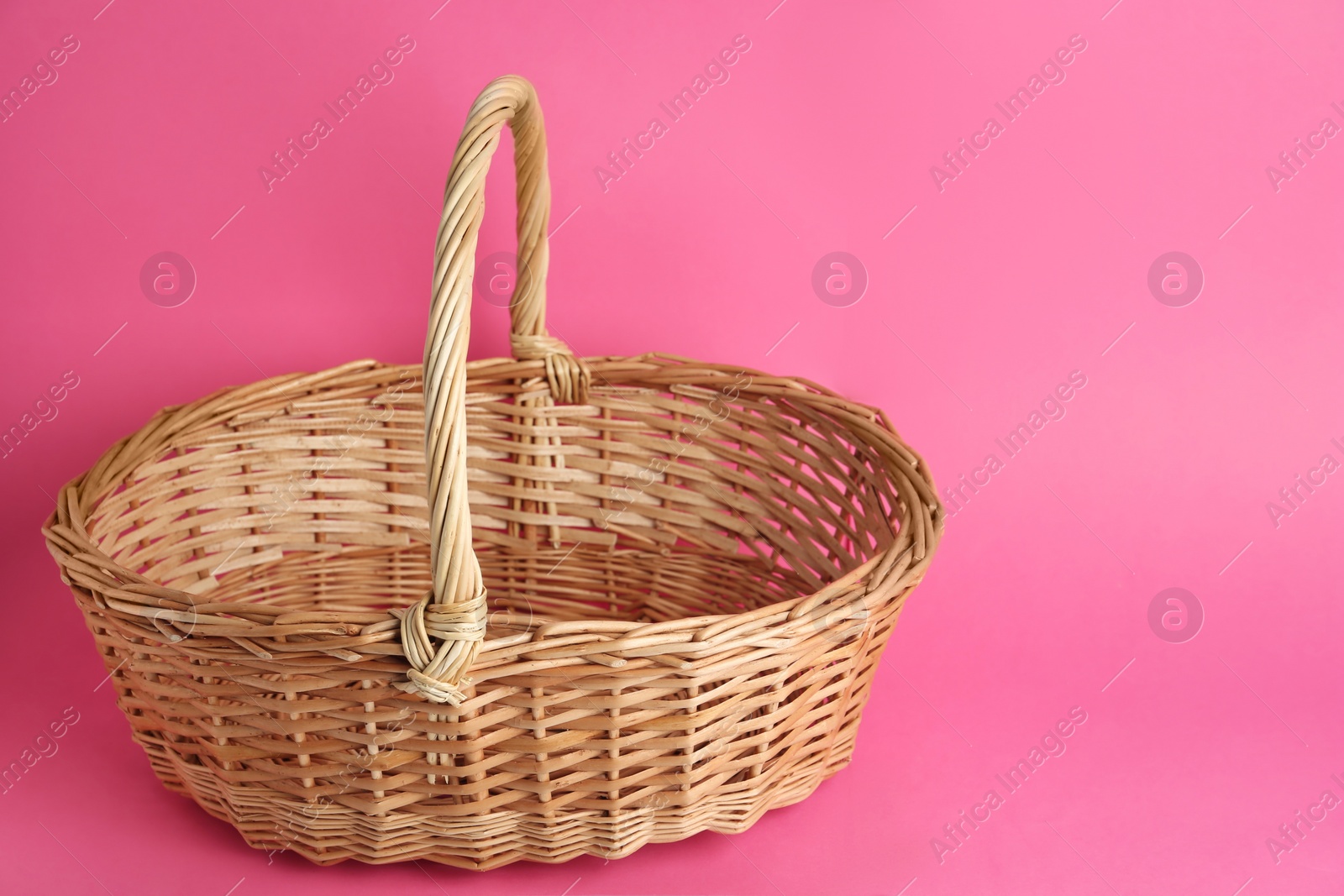 Photo of Empty wicker basket on pink background, space for text. Easter item